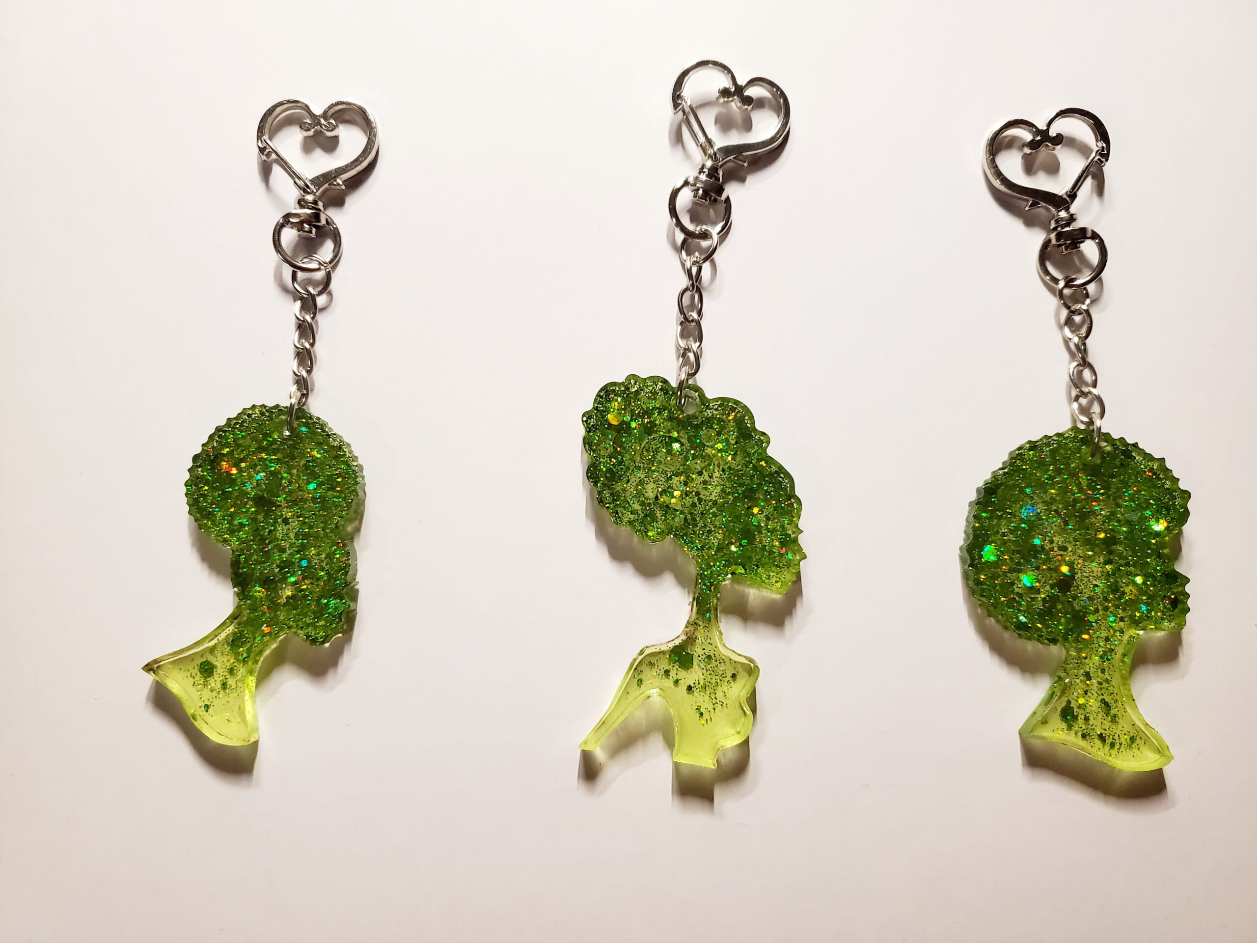3 heart-shaped keychain hooks with a resin mold shaped as women with green glitter decorations