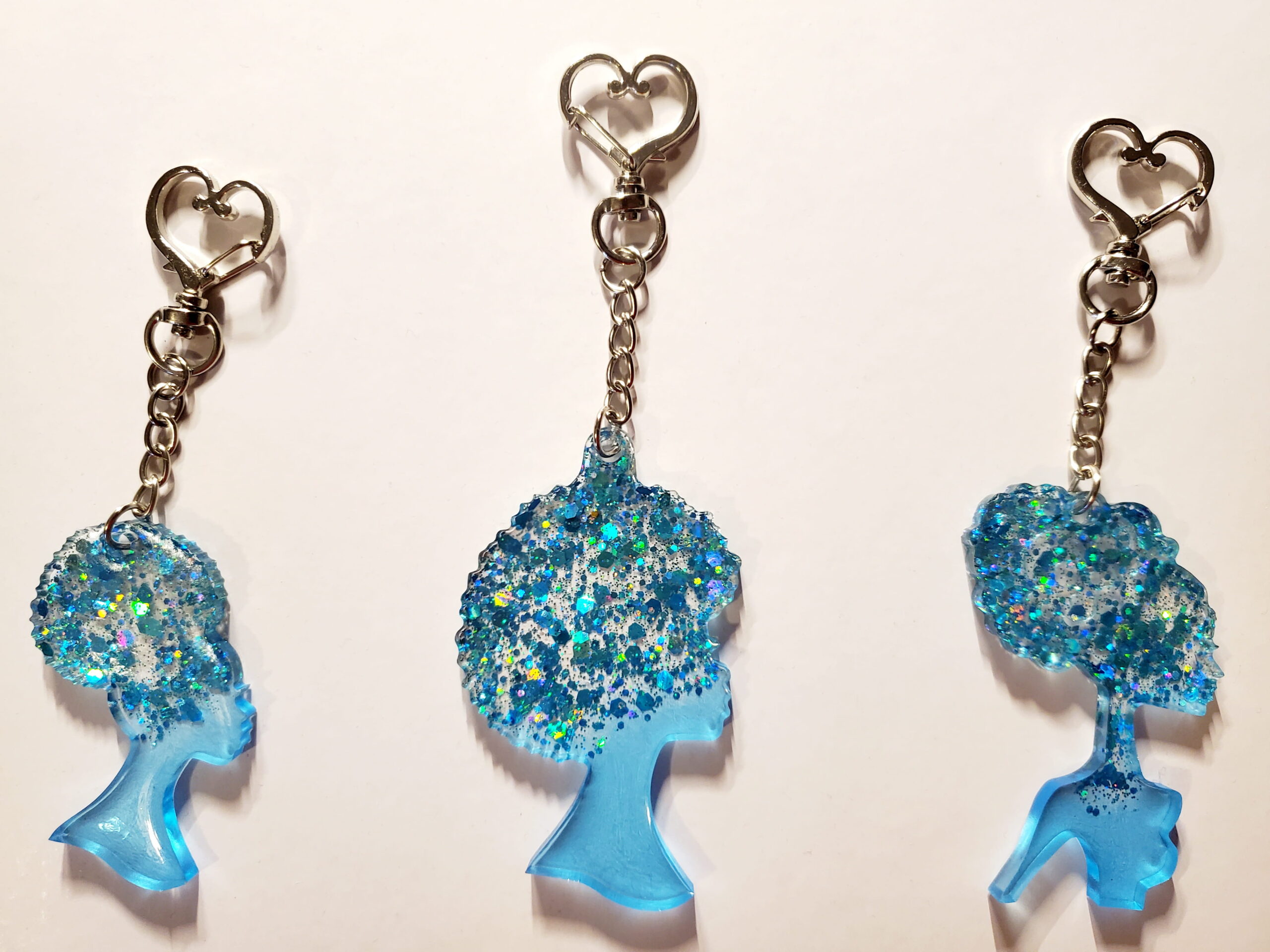 3 heart-shaped keychain hooks with a resin mold shaped as women with light blue glitter decorations