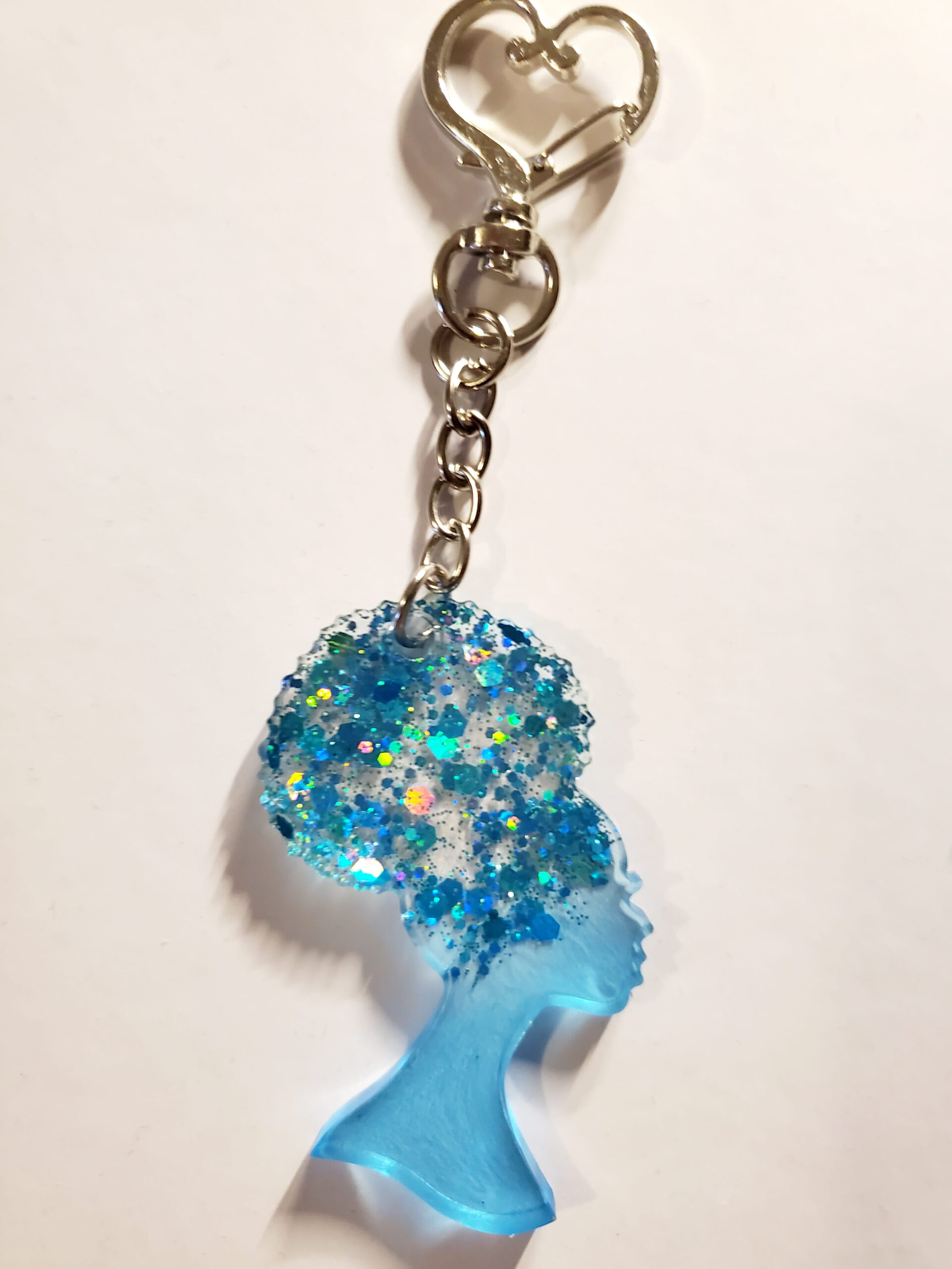 heart-shaped keychain hook with a resin mold shaped as a woman with up-do afro hairstyle with light blue glitter decorations