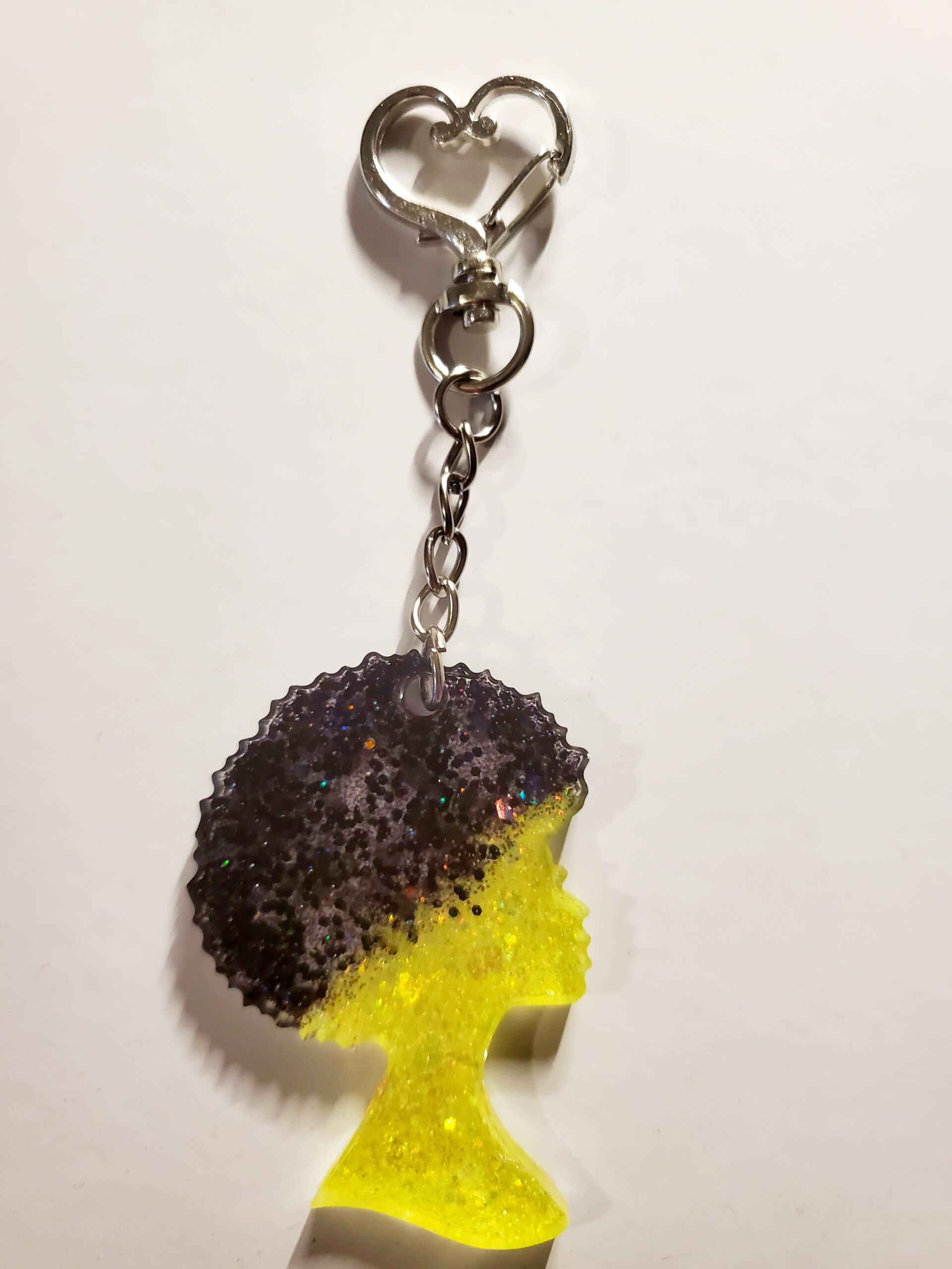heart-shaped keychain hook with a resin mold shaped as a woman with yellow and black glitter decorations