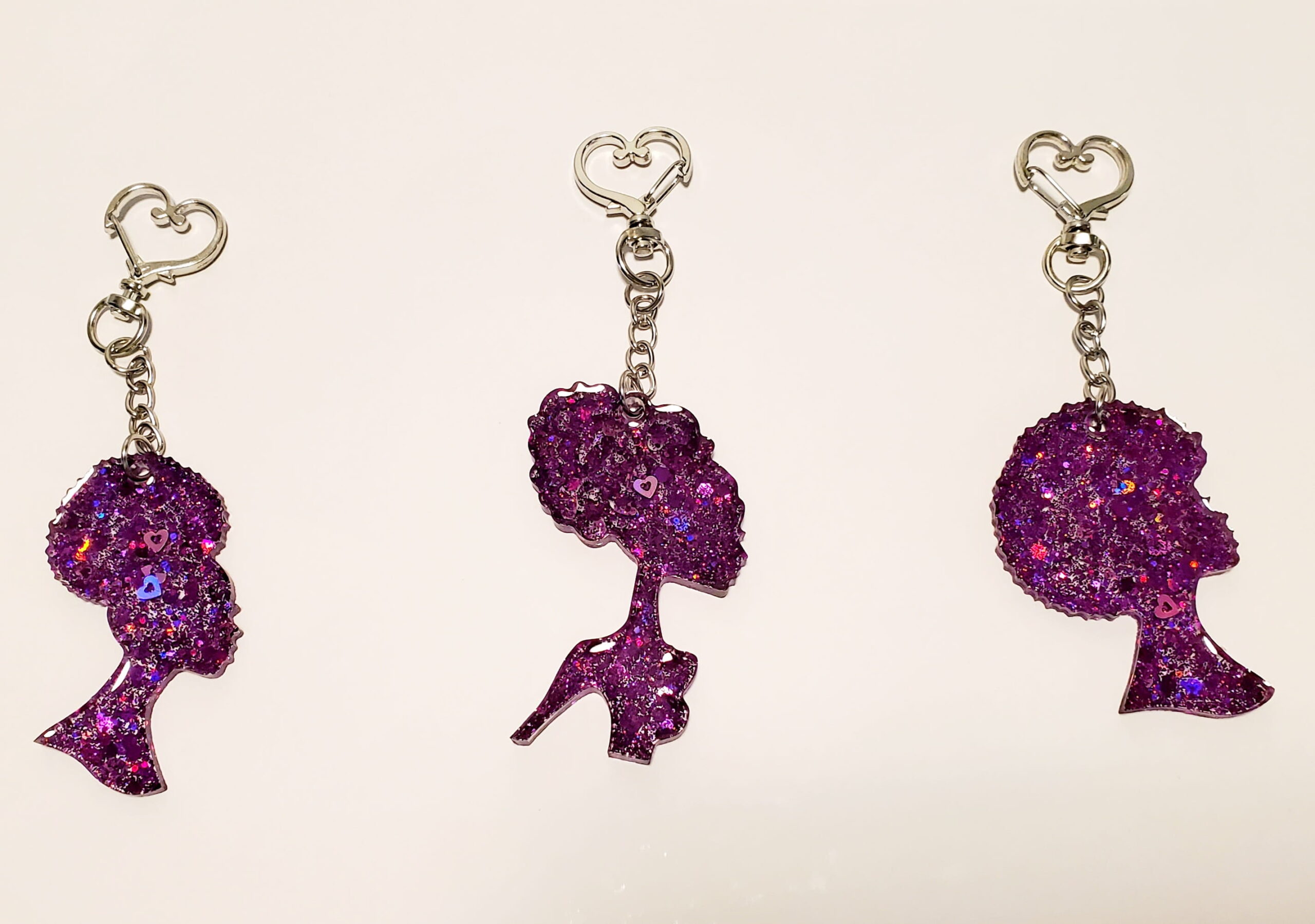 3 heart-shaped keychain hooks with a resin mold shaped as women with purple glitter decorations